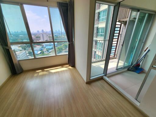 Empty bedroom with large windows and balcony access in a high-rise apartment