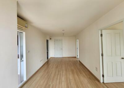 Spacious empty living room with wooden flooring and multiple doors