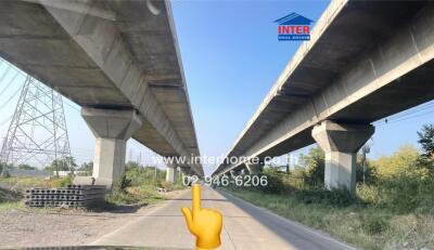 View under a large bridge with paved path and clear sky