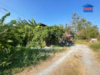 Rustic house surrounded by lush greenery with a for sale sign in the front yard