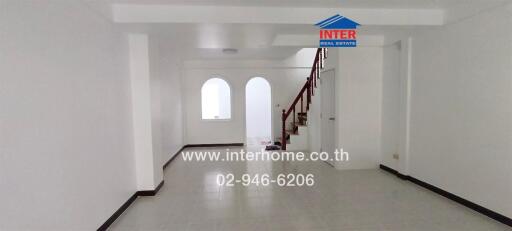 Spacious white living room with large arched windows and staircase