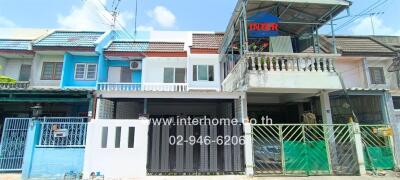 Exterior view of a modern two-story residential building with balconies and gated entries