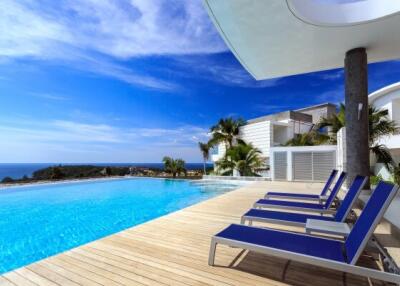 Luxurious outdoor pool area with panoramic sea views, modern sun loungers, and a lush tropical garden
