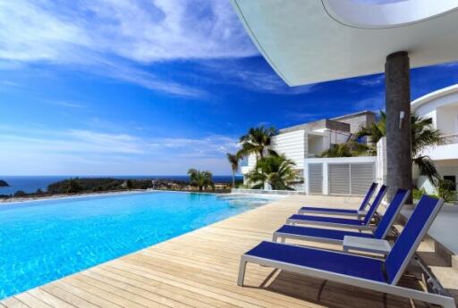 Luxurious outdoor pool area with panoramic sea views, modern sun loungers, and a lush tropical garden