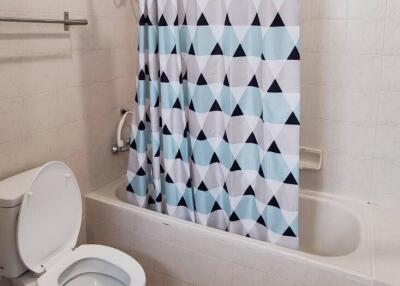 Modern bathroom with patterned shower curtain and white ceramic fixtures