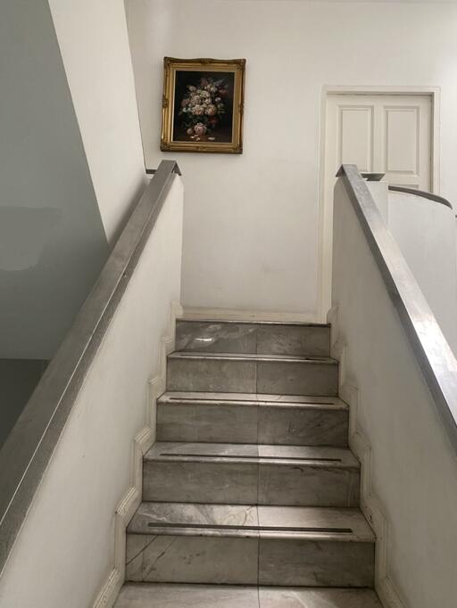 Marble staircase with white railing leading to upper floor in a home