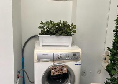 Compact laundry area with modern washing machine and organized storage space