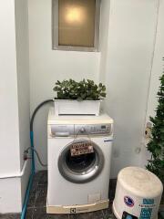Compact laundry area with modern washing machine and organized storage space
