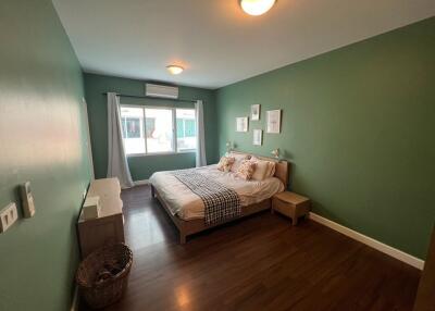 Cozy and well-lit bedroom with green walls and hardwood flooring