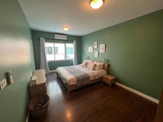 Cozy and well-lit bedroom with green walls and hardwood flooring