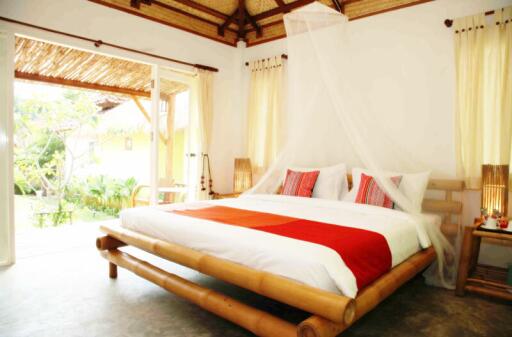 Spacious bedroom with bamboo bed frame and white mosquito netting