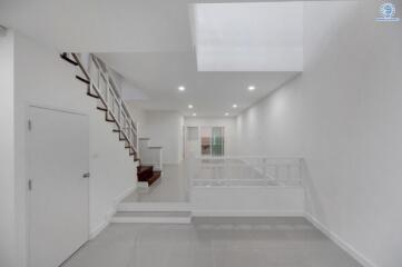 Modern white hallway with staircase and bright lighting