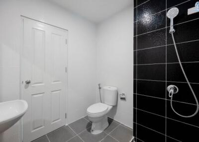 Modern bathroom with black tiled shower and white fixtures
