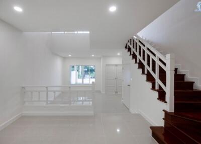 Spacious living room with white walls and dark wooden staircase