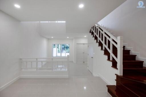 Spacious living room with white walls and dark wooden staircase