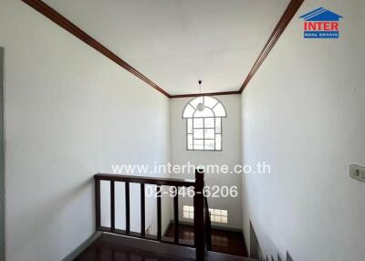 Spacious staircase area with classic wooden railing and arched window