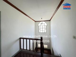Spacious staircase area with classic wooden railing and arched window