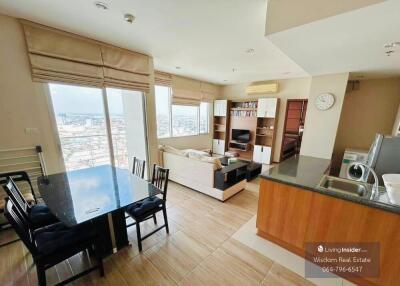 Spacious living room with kitchenette, dining area, and city view