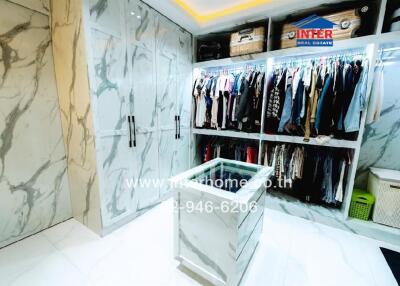 Spacious modern walk-in closet with extensive clothing storage and elegant marble walls