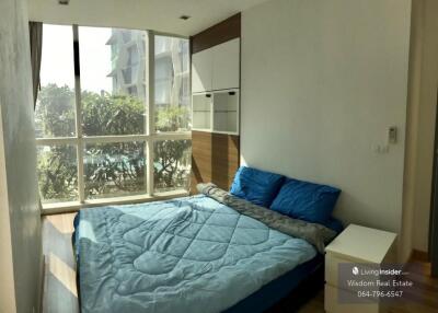 Modern bedroom with large window and view of surrounding buildings