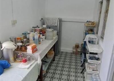 Cluttered kitchen space with white walls and patterned floor tiles