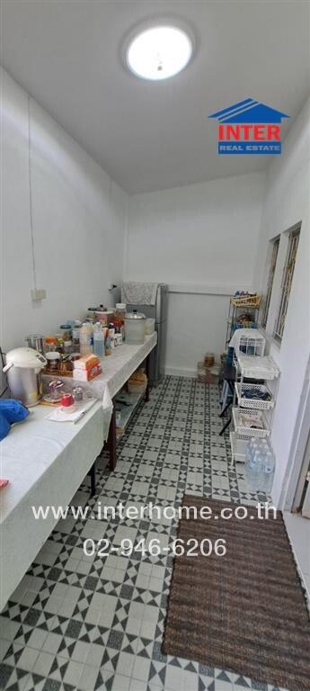 Cluttered kitchen space with white walls and patterned floor tiles