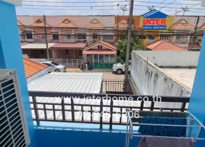 View from a balcony with protective railing overlooking a residential neighborhood and parking area