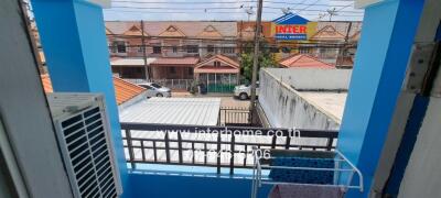 View from a balcony with protective railing overlooking a residential neighborhood and parking area