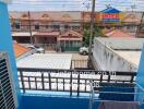 View from a balcony with protective railing overlooking a residential neighborhood and parking area