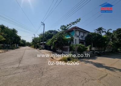 Quiet street view in front of a two-story house with lush greenery