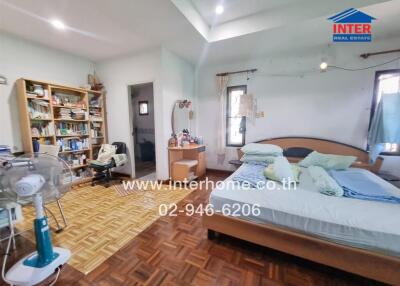 Spacious bedroom with extensive bookshelves and wooden flooring