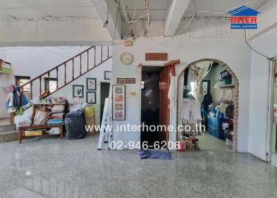 Spacious interior of a residential building with staircase and cluttered entrance area