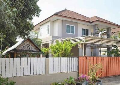 Exterior view of a suburban house with a fence and garden