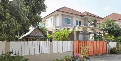 Exterior view of a suburban house with a fence and garden