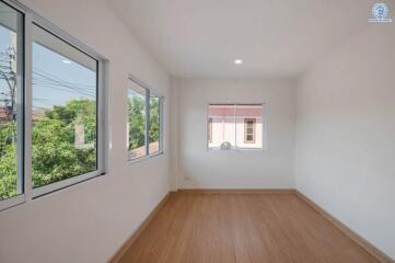 Bright empty bedroom with large windows and wooden flooring