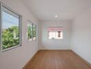 Bright empty bedroom with large windows and wooden flooring