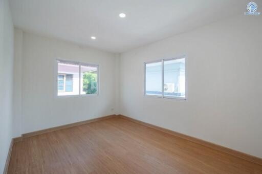 Bright and spacious empty bedroom with wooden flooring and large windows