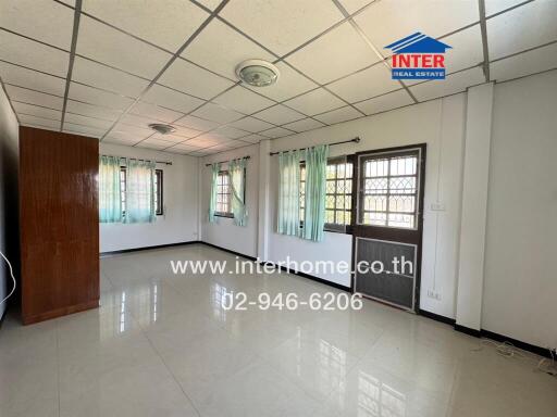 Spacious and well-lit empty living room with multiple windows and glossy tiled floor
