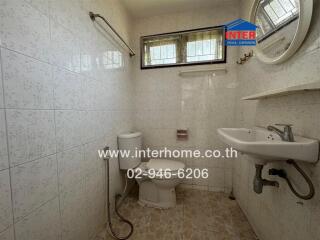 Clean and basic bathroom with white tiles, toilet, and sink