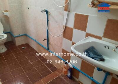 Under-construction bathroom with unfinished plumbing and tiling