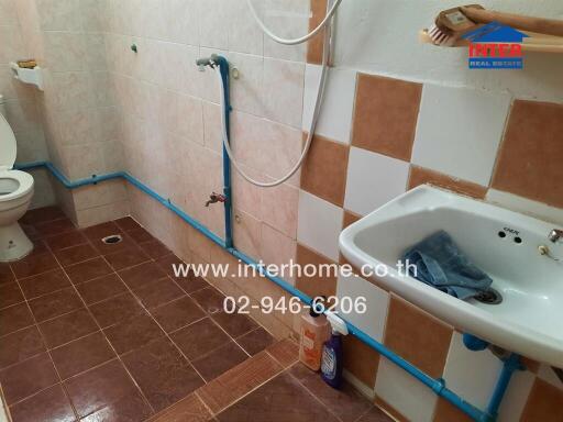 Under-construction bathroom with unfinished plumbing and tiling