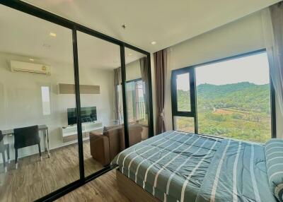 Spacious bedroom with large windows overlooking green hills