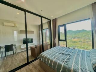Spacious bedroom with large windows overlooking green hills