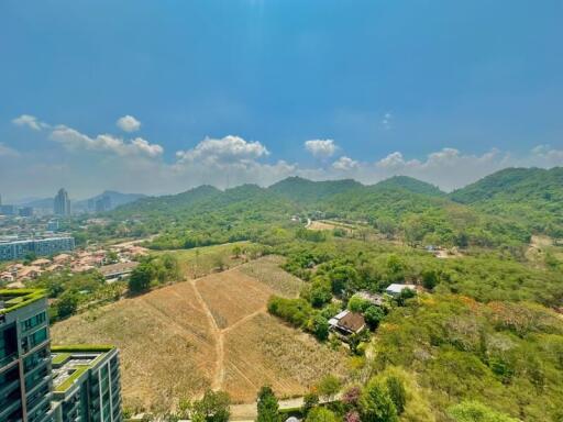 Panoramic view from a high-rise overlooking lush greenery and city buildings