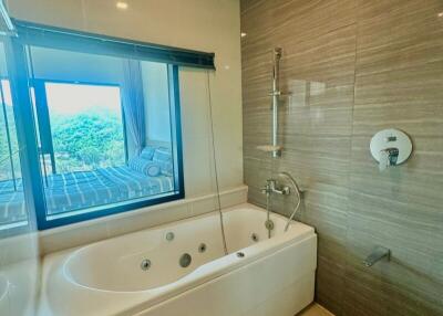 Spacious modern bathroom with bathtub and large window showing outdoor view