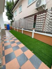 Well-maintained outdoor patio area with decorative tiles and artificial grass