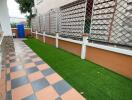 Well-maintained outdoor patio area with decorative tiles and artificial grass