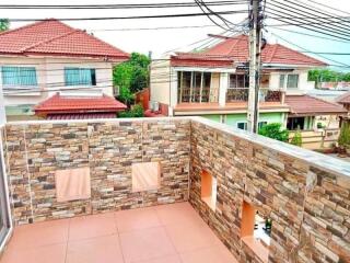 Spacious balcony with stone wall and view of neighboring houses