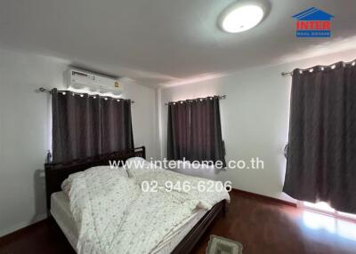 Spacious bedroom with modern furnishings, including a large bed, air conditioner, and ample lighting