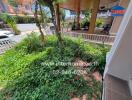 Spacious outdoor area with lush greenery and a covered carport nearby